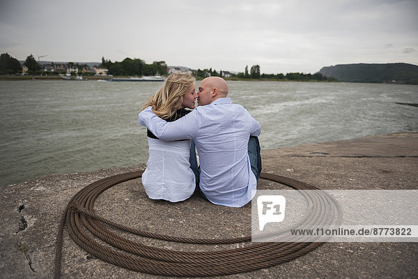 Germany  Rhineland-Palatinate  young couple kissing at waterside of Rhine river