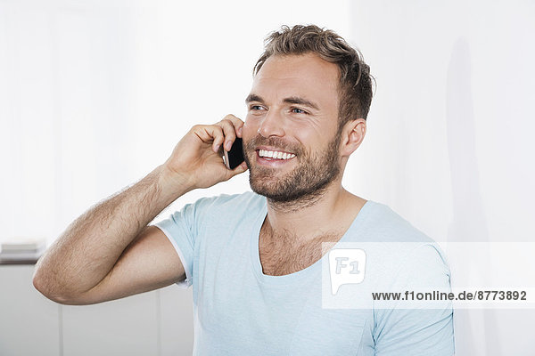 Portrait of young man leaning against wall telephoning with smartphone