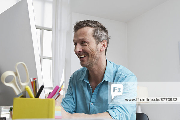 Happy man at home sitting at desk with computer