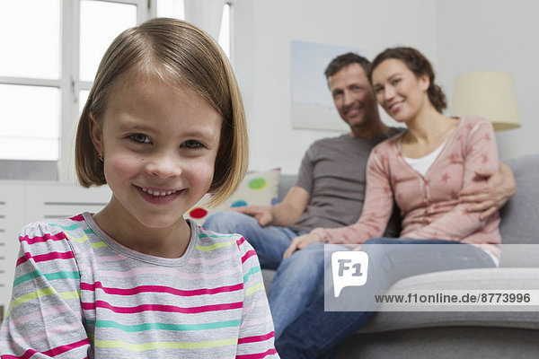 Blond girl in living room with parents in background