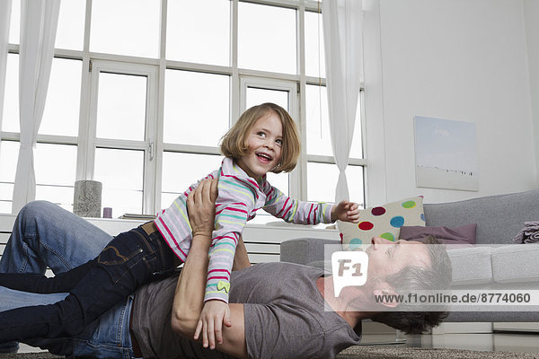 Playful father and daughter in living room