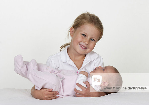 Porträt eines lächelnden kleinen Mädchens mit neugeborener Schwester