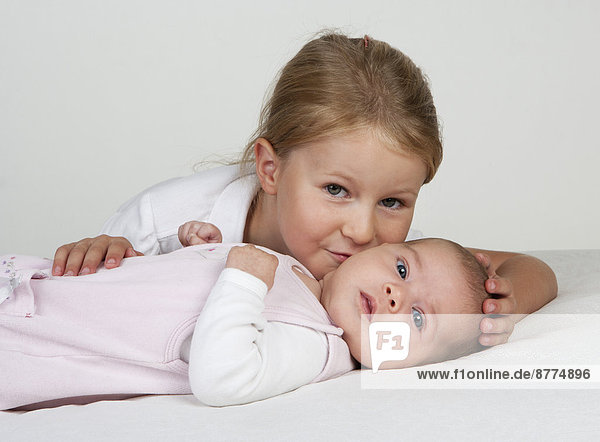 Porträt des kleinen Mädchens  das die neugeborene Schwester küsst.