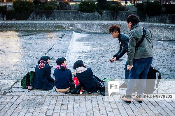 Men talking to girls Kamo river at Pontocho Kyoto  Japan.