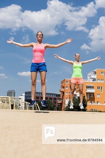 Zwei junge Frauen bei Sprungübungen im Park