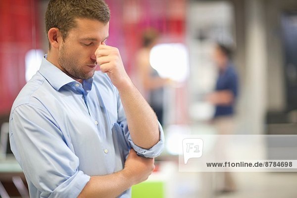 Young businessman looking stressed in office