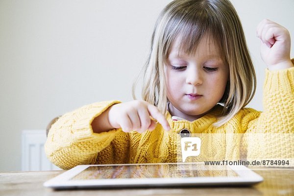 Junges Mädchen am Küchentisch mit digitalem Tablett