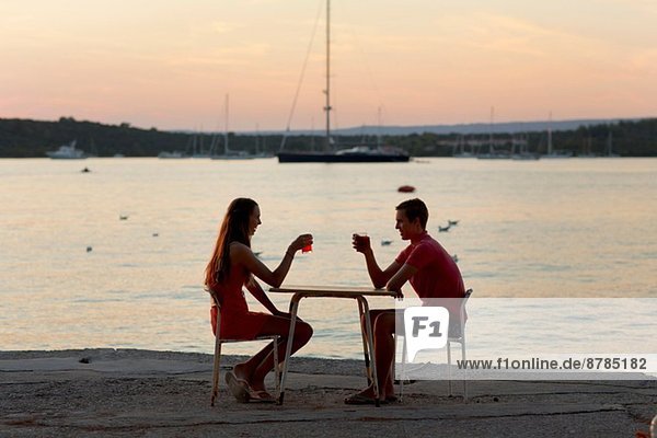 Junges Paar  das sich gegenseitig an der Mole toastet  Loviste  Kroatien