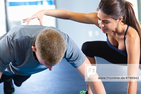 Ein Paar hilft sich gegenseitig im Fitnessstudio.