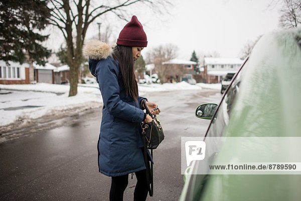 Junge Frau auf der Suche nach Autoschlüsseln in ihrer Tasche