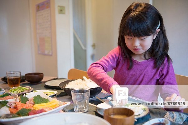 Girl selecting meal from dishes on dining table