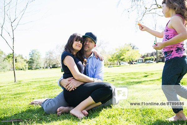 Mittleres erwachsenes Paar im Park sitzend mit kleiner Tochter