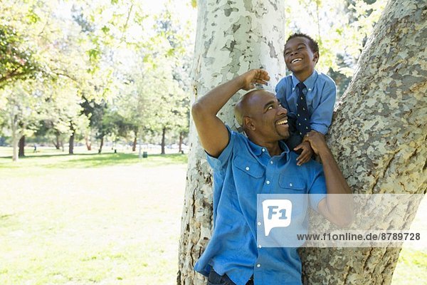 Erwachsener Mann und Sohn klettern im Park