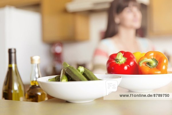 Mittlere erwachsene Frau in der Küche mit Gemüseschüsseln auf der Theke