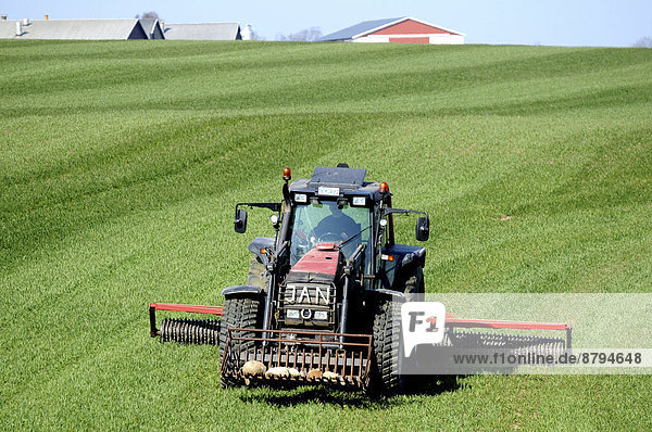 Traktor mit Cambridgewalze bei der Arbeit auf einem grünen Feld im Frühjahr Snårestad Ruuthsbo Schonen Schweden