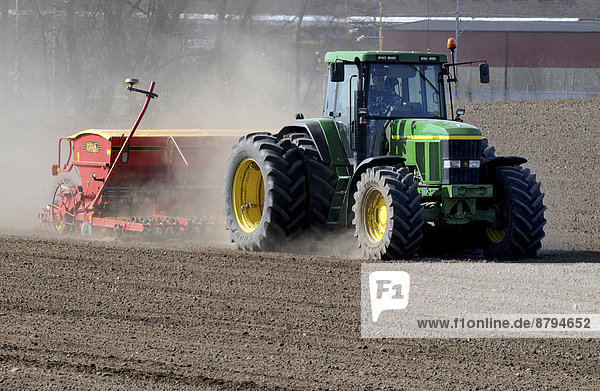 Traktor mit Sämaschine bei der Arbeit auf einem Feld im Frühjahr Köpingebro Schonen Schweden