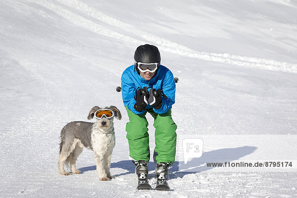 A skier and his dog with snow goggles on a ski slope  Carosello 3000  Livigno  Lombardy  Italy