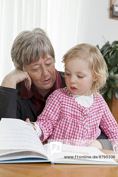 Großmutter liest der 3-jährigen Enkeltochter aus einem Buch vor