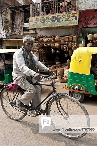 Indian man riding bicycle street scene in city of Varanasi  Benares  Northern India