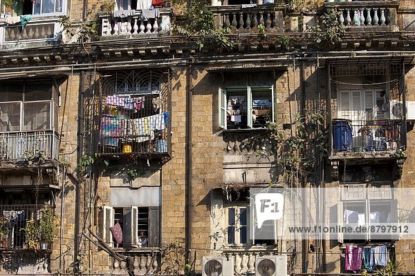 Tenement block traditional chawl housing scheme with air conditioning units and man in window in Parel area of Mumbai  India