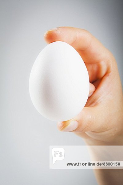 Frauenhand hält ein weisses Ei
