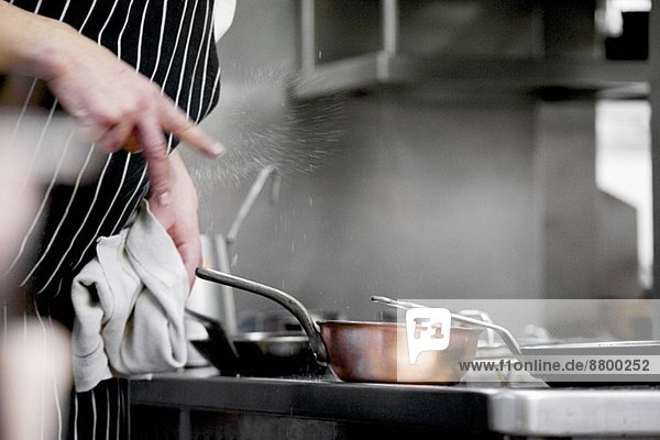 Chef clicking salt into dish during service in working restaurant