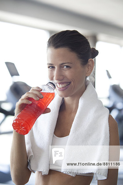 Frau hydratisiert mit Sportgetränk im Fitnessstudio