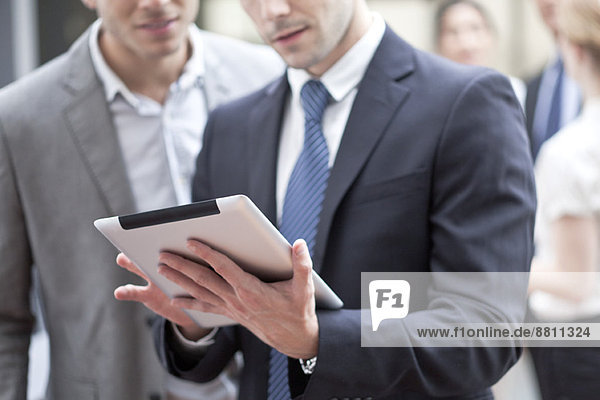 Businessman showing colleague digital tablet