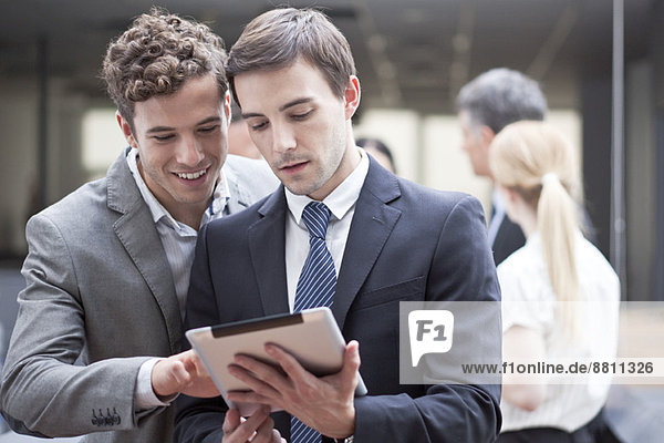 Businessman showing colleague digital tablet