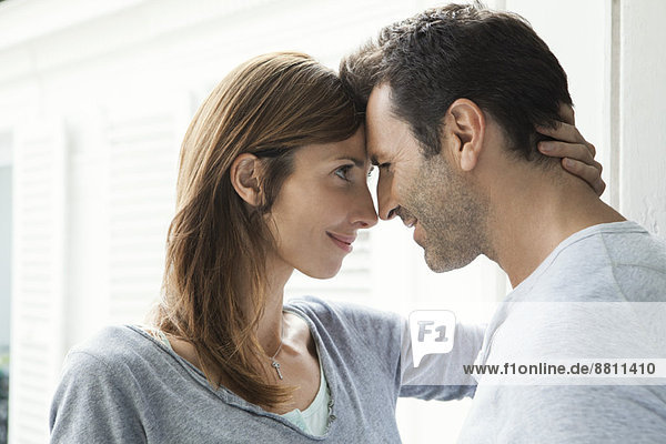 Couple touching noses by window