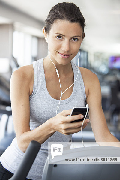 Young woman listening to music while using step climber at gym