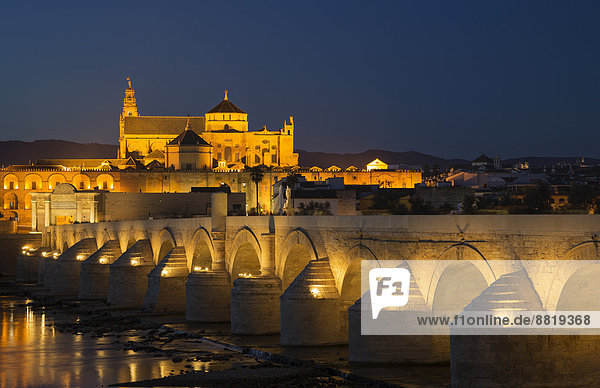 Puente Romano  Brücke über den Fluss Guadalquivir mit der Mezquita hinten  beleuchtet in der Abenddämmerung  Córdoba  Andalusien  Spanien