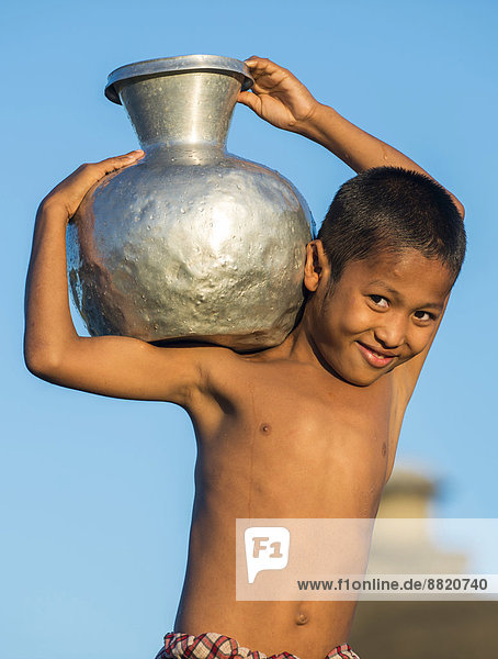 Smiling boy carrying water in a water container made of aluminium  Mrauk U  Sittwe District  Rakhine State  Myanmar