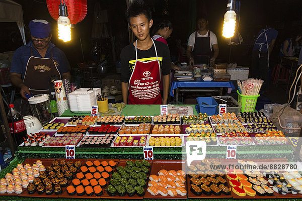 Man selling sushi at a stand in the Night Market in Walking Street  Chiang Rai  Chiang Rai Province  Northern Thailand  Thailand