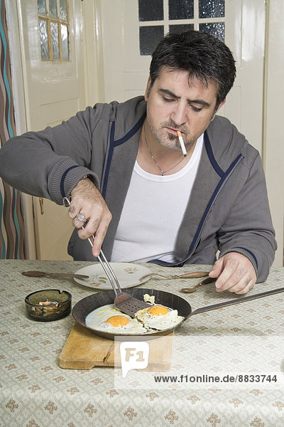 Portrait of man with bad habit sitting at breakfast table
