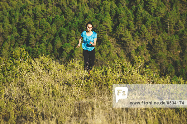 Young female jogger on the move in front of forest