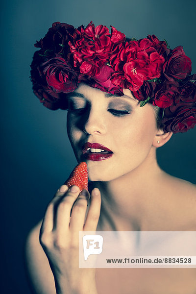 Porträt einer jungen Frau mit roten Blumen und Blick auf Erdbeere