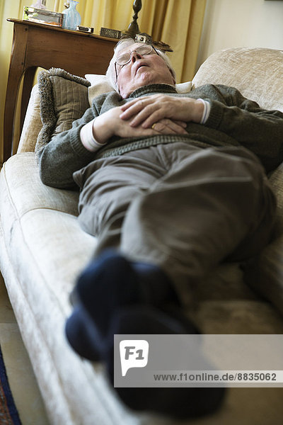 Senior man having midday sleep on sofa