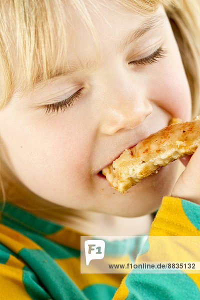 Porträt eines kleinen Mädchens beim Essen mit geschlossenen Augen