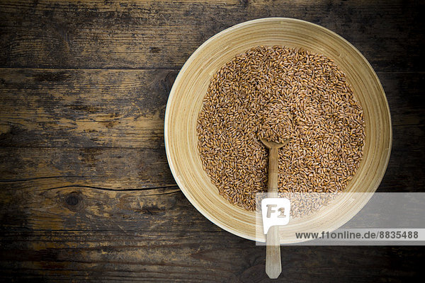 Bowl of spelt grains on dark wooden table  elevated view