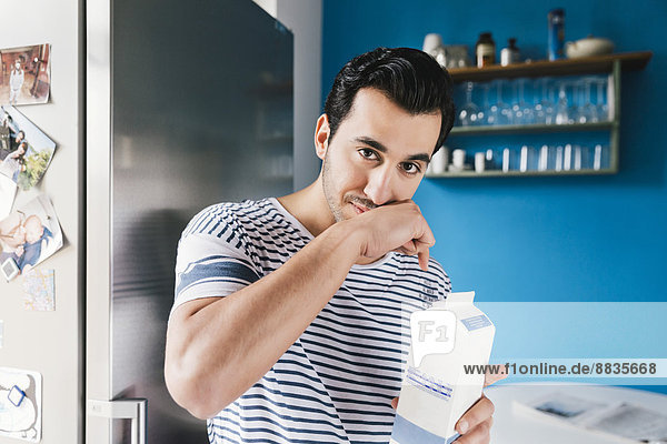 Portrait of young man wiping off his milk moustache