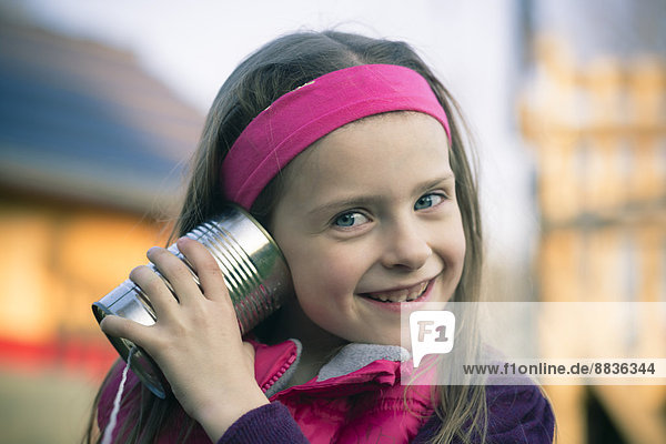 Porträt eines kleinen Mädchens mit Blechdosentelefon
