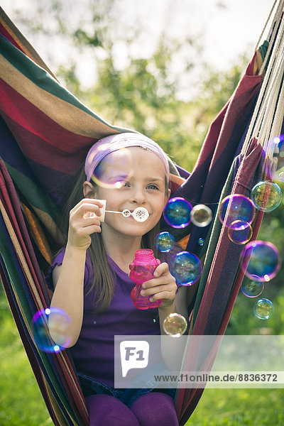 Porträt eines lächelnden kleinen Mädchens  das Seifenblasen bläst.