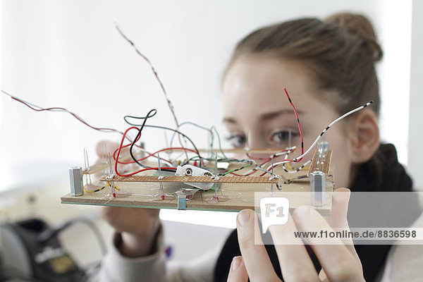 Halteelement für eine junge Frau für einen optischen Sensor in einer Elektronikwerkstatt