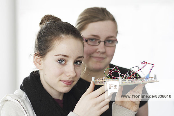 Zwei junge Frauen halten einen optischen Sensor in einer Elektronikwerkstatt.