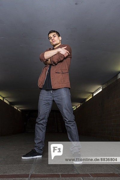 Young breakdancer with crossed arms standing in underpass