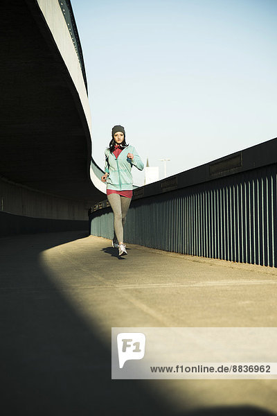 Young female jogger on the move on a bridge
