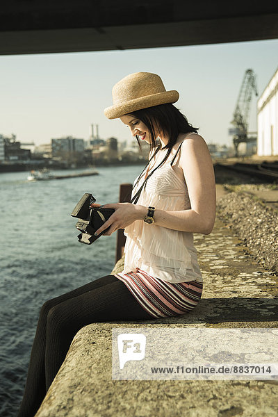 Portrait of young woman with old camera wearing summer hat