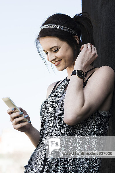 Porträt einer lächelnden jungen Frau mit Smartphone
