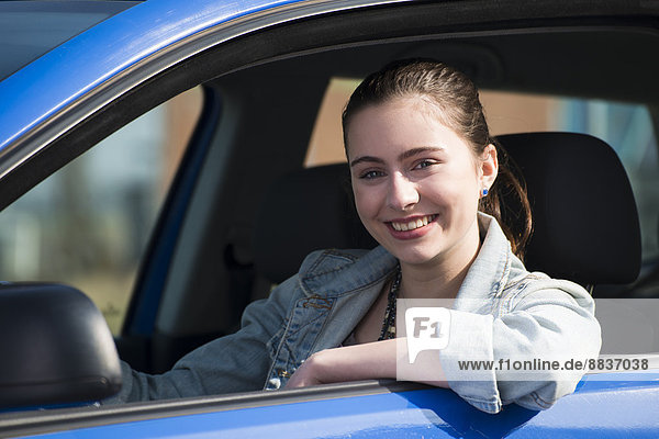 Smiling teenage girl sitting in car  partial view